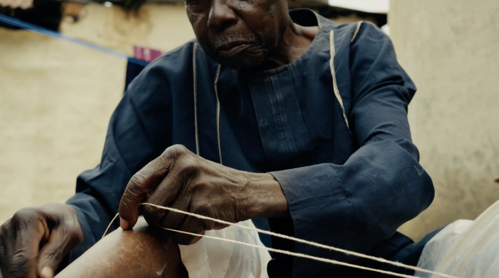 Close view of the master weaver's hands working thread between his fingers