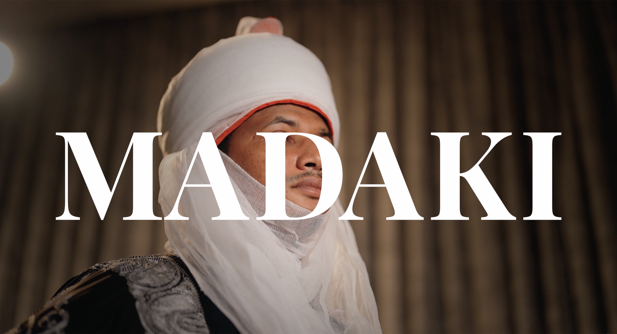 Portrait of the Madaki in a white turban, the film title across the frame