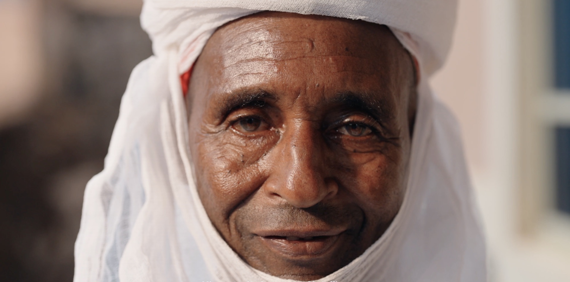 Close portrait of an elder in a white turban, looking directly into the camera